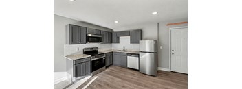 A modern kitchen with stainless steel appliances and wooden flooring.