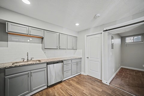 A kitchen with white cabinets and a wooden floor.