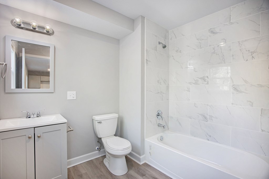 A white bathroom with a marble tile shower.at Palisades Apartments, Kansas City
