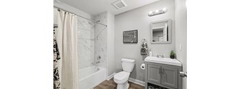 A bathroom with a white toilet, a white sink, and a shower with a curtain.