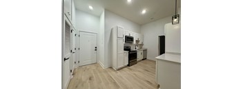 A kitchen with white cabinets and a wooden floor.