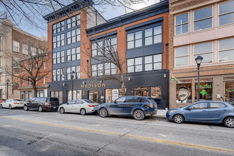 Cars parked on the street in front of a building with a sign that says "Nadison".