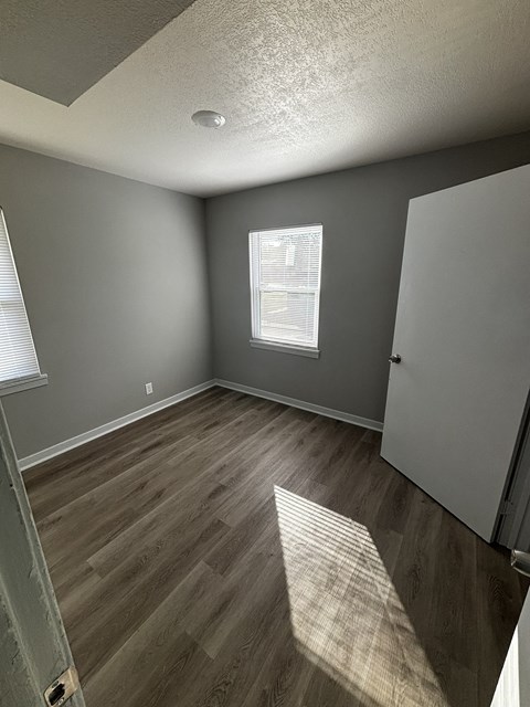 an empty room with wooden floors and gray walls