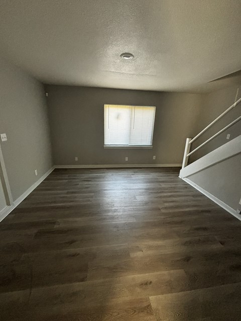 an empty room with wood floors and a window