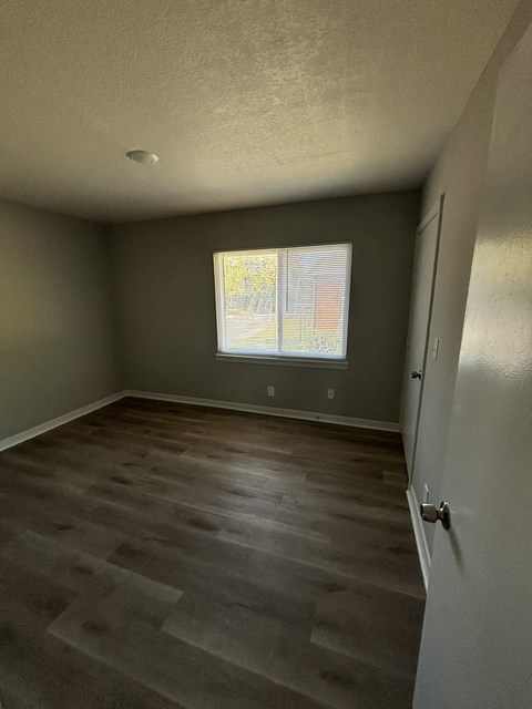 an empty room with wooden floors and a window