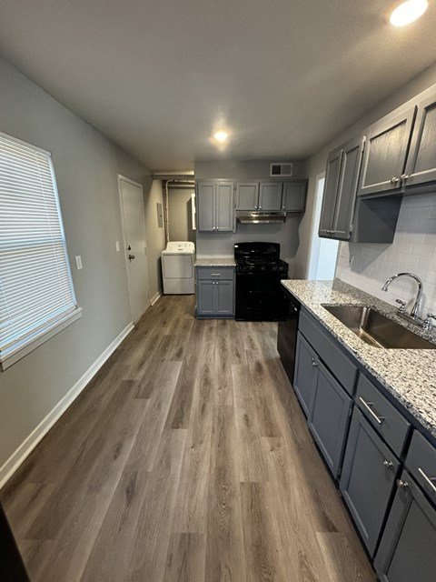 a kitchen with gray cabinets and wooden floors and a black stove
