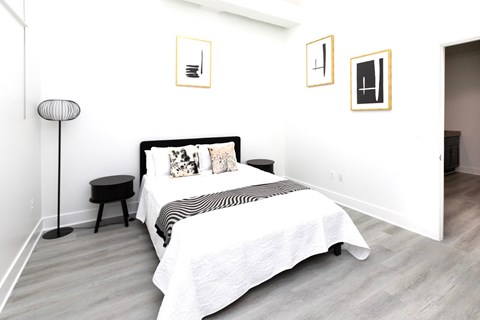 A bedroom with a bed, a side table, and pictures on the wall.