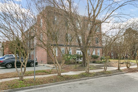 A large brick building with a tree in front of it at Shipyard Shores Apartments, Apartments, Newport News, VA