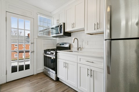 A kitchen with white cabinets and a stainless steel refrigerator.