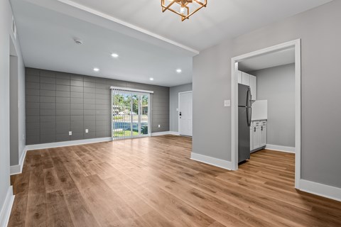 A spacious kitchen with a refrigerator and a dining table with chairs.
