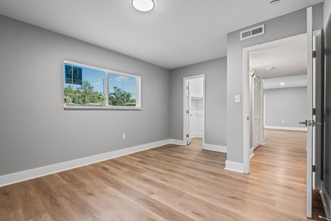 A room with wooden floors and a window showing trees outside.
