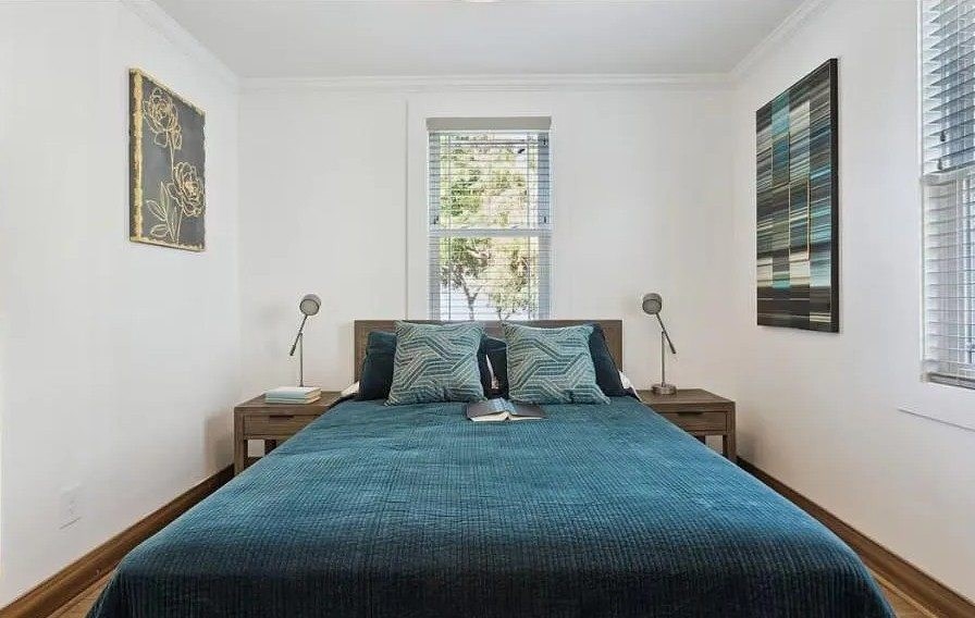 A bedroom with a bed, two lamps, and a window.