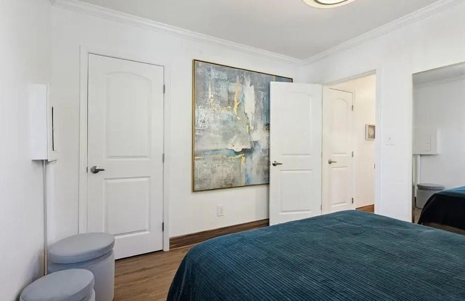 A bedroom with a bed, toilet, and painting on the wall.