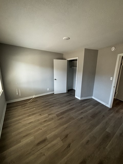 an empty bedroom with wooden floors and grey walls