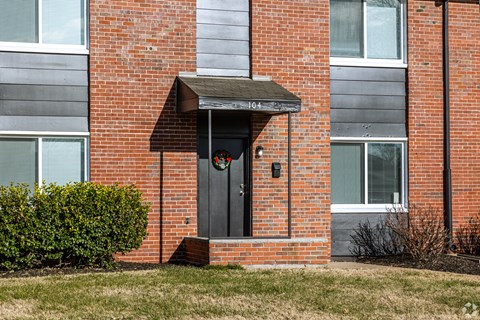 A red brick building with a black door and a small porch. at Blacklark Apartments, Apartments, Kansas City, KS