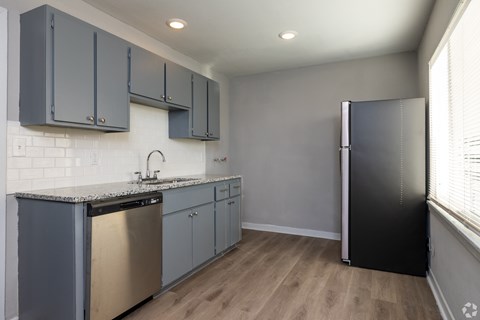 A kitchen with a black refrigerator and a stainless steel dishwasher.