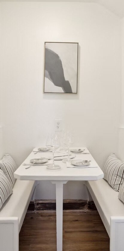 A breakfast nook, white dining table with plates and glasses on it.