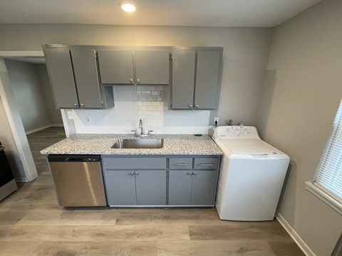 a small kitchen with a sink and a washer and dryer