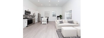 A modern kitchen with a white color scheme and a living room with a white couch.