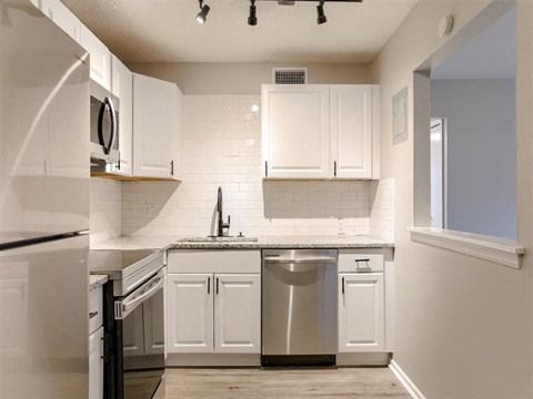a kitchen with white cabinets and stainless steel appliances