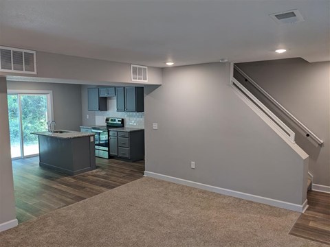 a living room with a kitchen and stairs