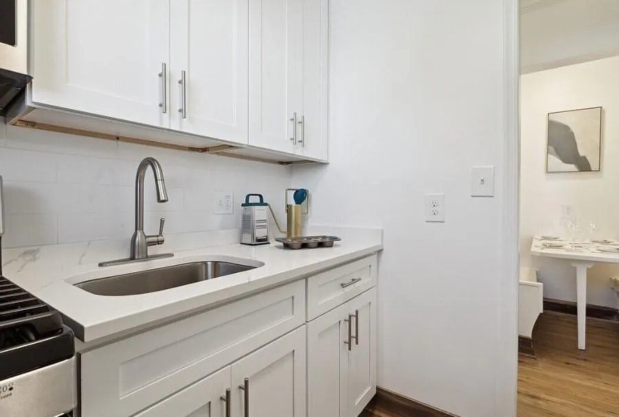 A kitchen with white cabinets and a stainless steel sink.