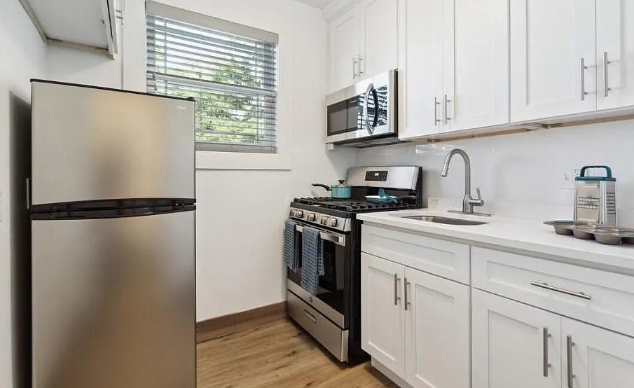 A kitchen with a stainless steel refrigerator, a stove, and a microwave.