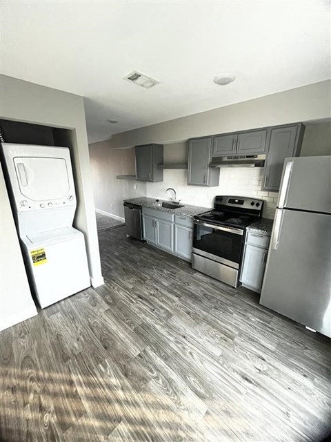 a small kitchen with stainless steel appliances and a stackable washer and dryer