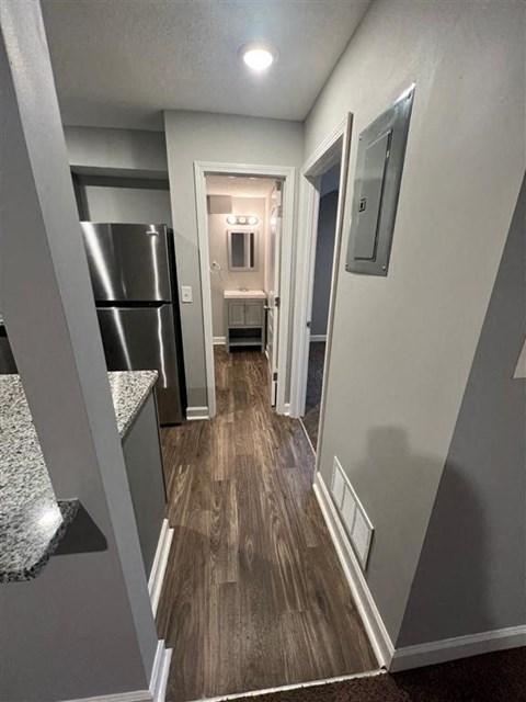 a hallway with a kitchen and a refrigerator
