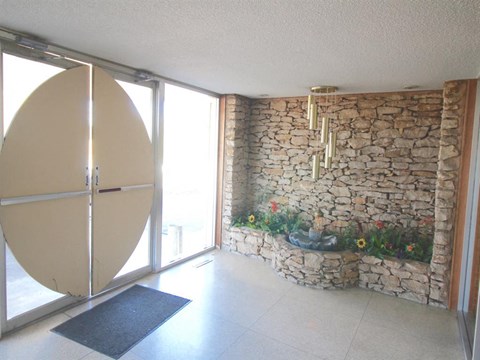 a living room with a stone wall and a refrigerator
