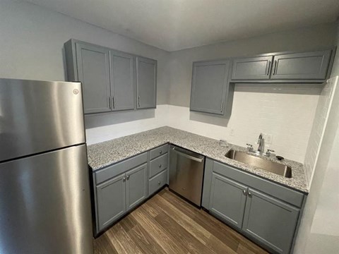 a kitchen with gray cabinets and a stainless steel refrigerator