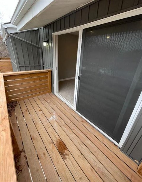 a patio with a sliding glass door and a wooden deck