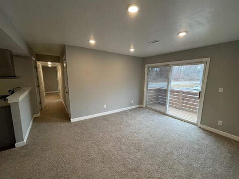 an empty living room with a large window and carpet