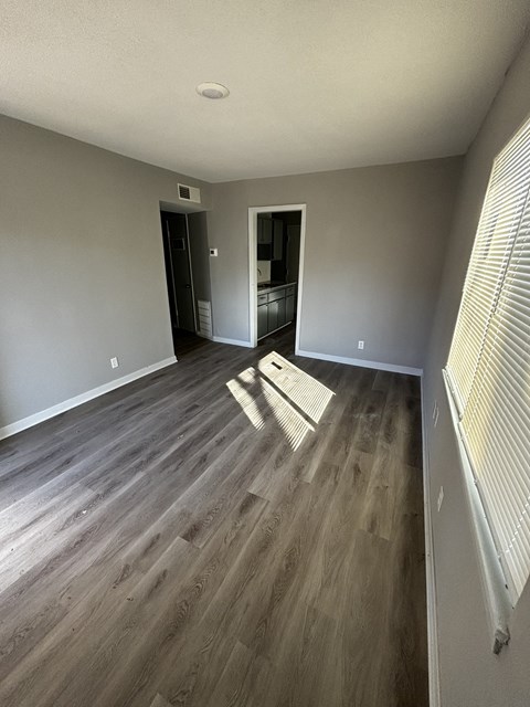 an empty living room with hardwood floors and grey walls