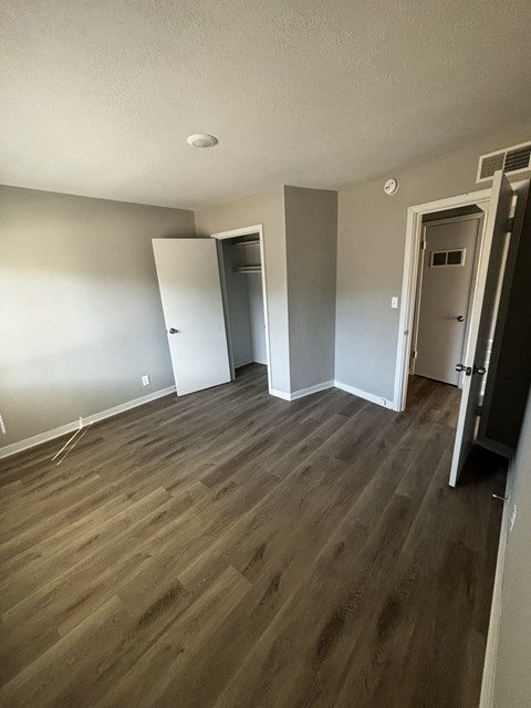 an empty bedroom with wood floors and white walls