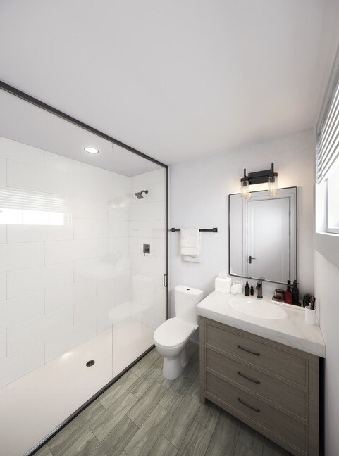 A modern bathroom with a white toilet, sink, and a walk-in shower.