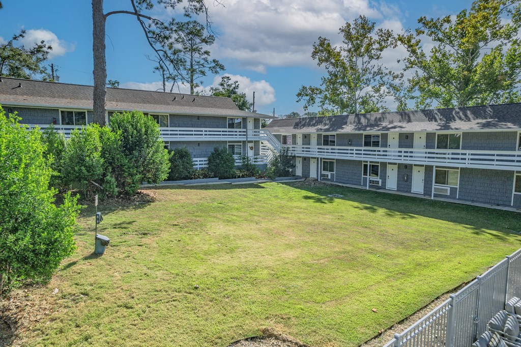 A grassy area in front of a building with a fence.