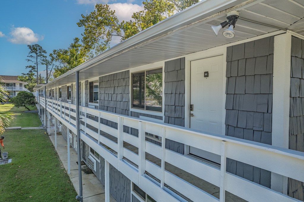 A white house with a balcony and a person standing on the left side.