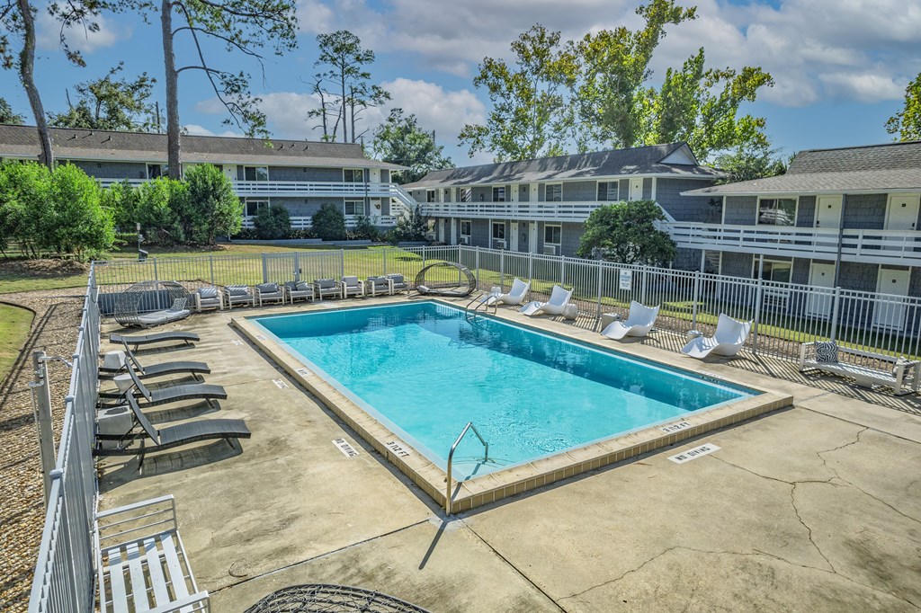 A large swimming pool surrounded by lounge chairs and trees.