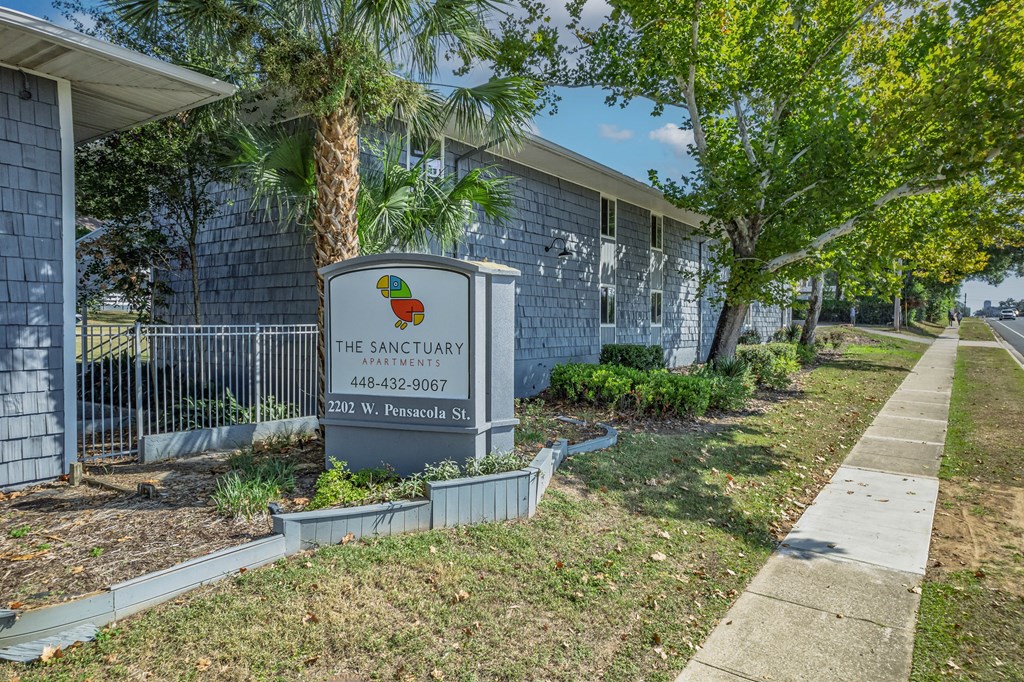 A sign for The Sanctuary apartments is in front of a building.
