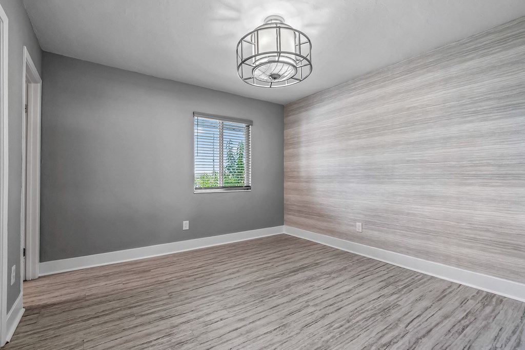 A room with wooden flooring and a window with blinds.