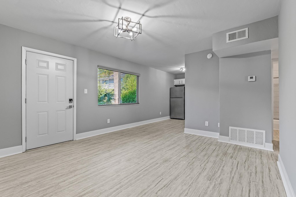 A room with a white door and a window with a view of trees.