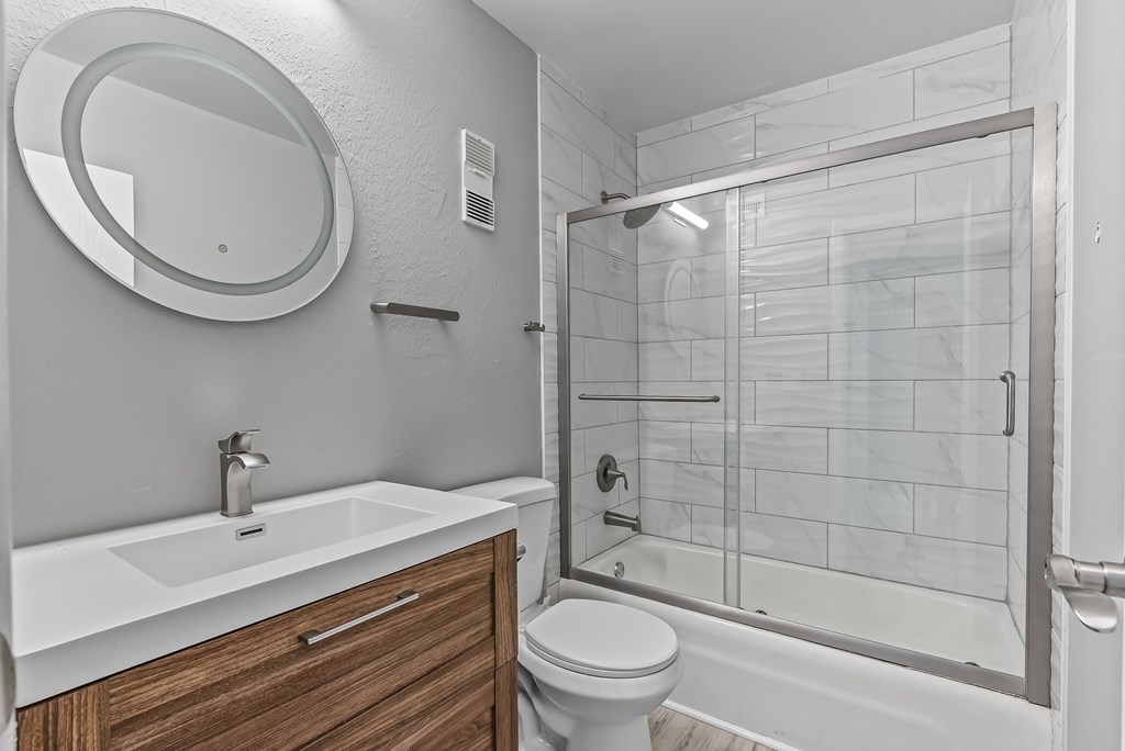 A bathroom with a white sink, toilet, and a glass shower stall.