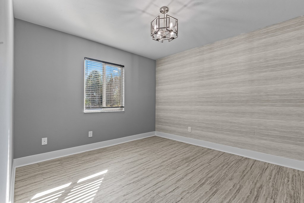 A room with a wooden floor and a window with blinds.