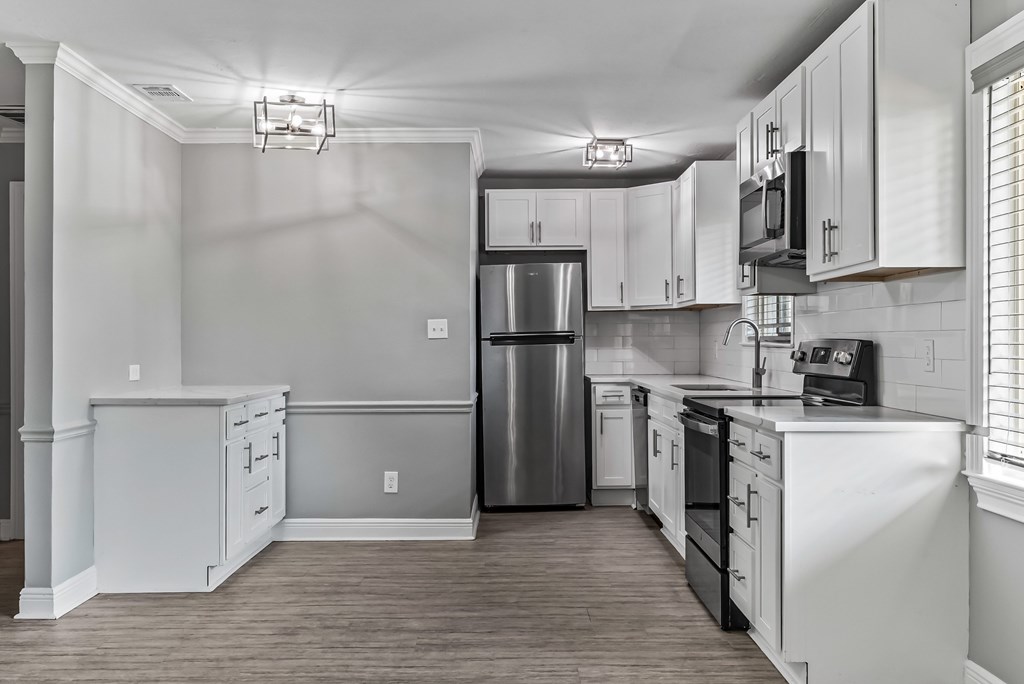 A kitchen with white cabinets and a stainless steel refrigerator.