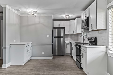 A kitchen with white cabinets and a stainless steel refrigerator.