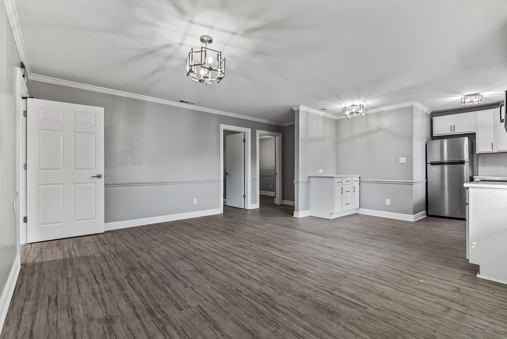 A spacious kitchen and living room with wood flooring and white walls.