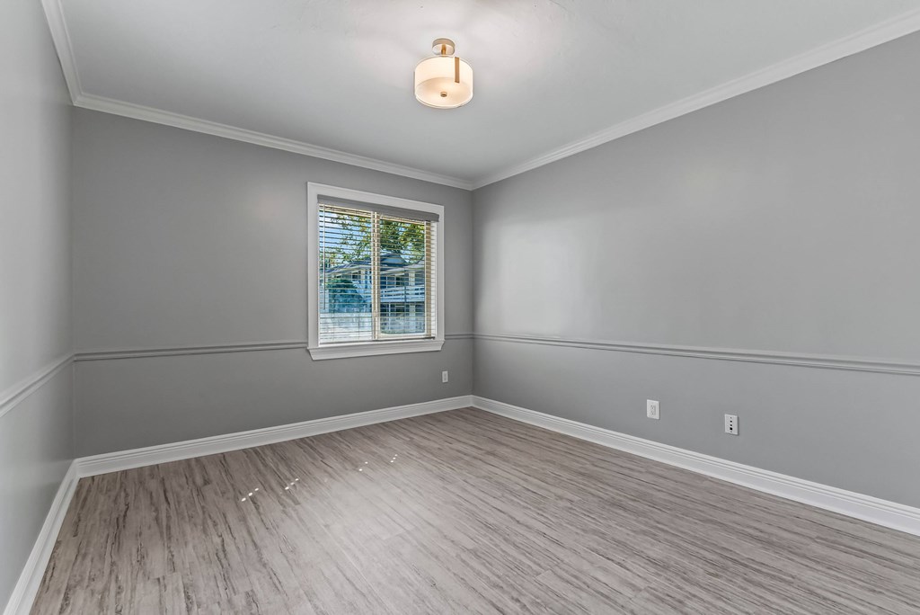 A room with a window and a wooden floor.