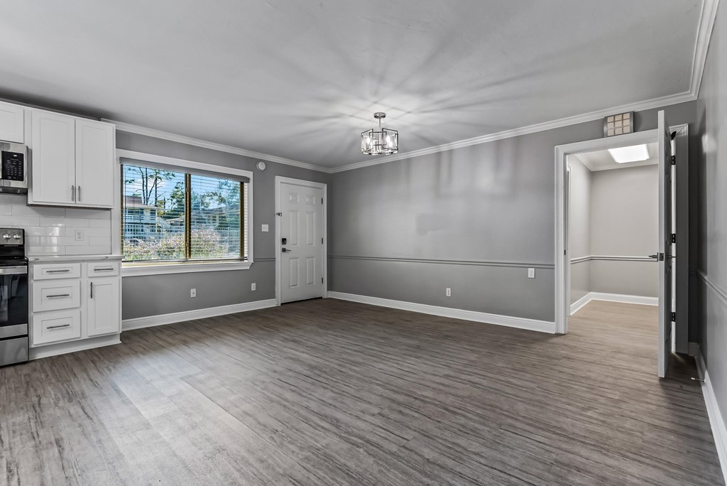 A spacious room with wooden flooring and white walls.