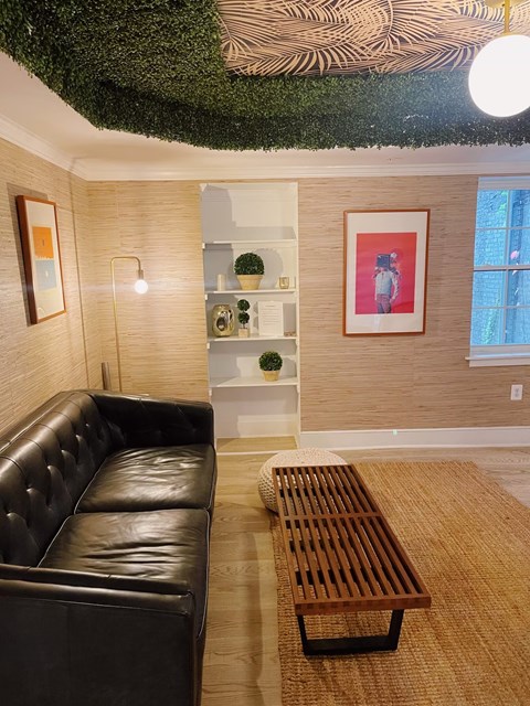 A living room with a black leather couch and a wooden coffee table.